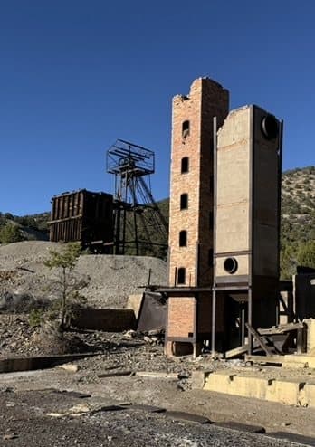 Historic mine structures standing against a mountain sky